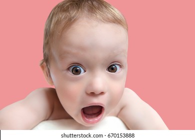 Close Up Of Very Surprised, Shocked Baby Boy With Open Mouth And Big Eyes Looking At Viewer, Pink Background