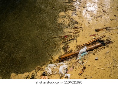 Close Up View From Above Of Polluted Dirty Muddy Water With Debris, Garbage And Plastic.