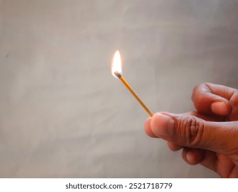 Close up view of an adult man's hand holding a lit match - Powered by Shutterstock