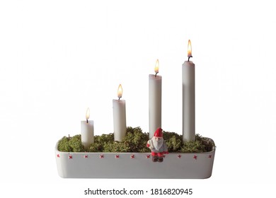 Close up view of advent candlestick decorated with little figure of Santa Clause and green moss.
