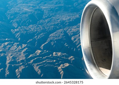 Close up view of an aircraft engine while flying over mountainous terrain in the Western United States