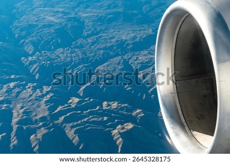 Close up view of an aircraft engine while flying over mountainous terrain in the Western United States