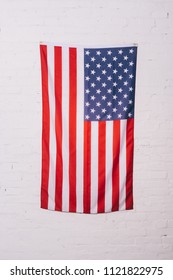close up view of american flag hanging on white brick wall