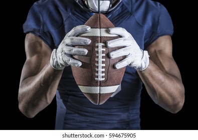 Close up view of an American Football player holding a football. Selective focus on the laces of the football and the wide receiver gloves. Shot on a black background - Powered by Shutterstock