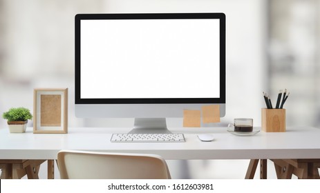Close up view of artist workspace with blank screen computer, office supplies and decoration on white desk with blurred office room background  - Shutterstock ID 1612603981