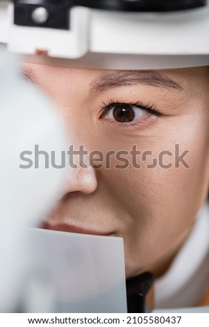 close up view of asian optometrist working with vision screener on blurred foreground