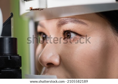 close up view of asian woman checking eyesight on blurred vision screener