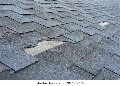 Close Up View Of Asphalt Shingles Roof Damage That Needs Repair.