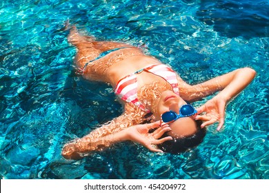 Close up view of an attractive young woman floating on the water dressed in american flag colored bikini swimsuit. - Powered by Shutterstock