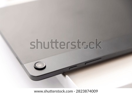 A close up view of the back camera lens and side buttons of a dark gray digital tablet