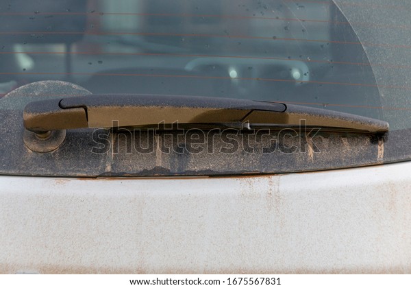 a close up view of the back of a car\
window with mud covering the windscreen wiper\
