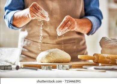 Close up view of baker is working. Homemade bread. Hands preparing dough on wooden table. 