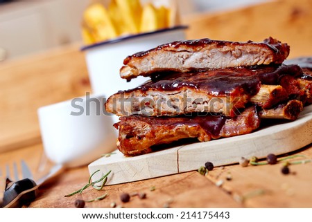 Close up view of barbecue ribs with fries and sauce on a old wooden table