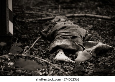 Close Up View Of Bare Feet Of Dead Body Sticking Out Of Bag Or Rug, Thrown In Woods