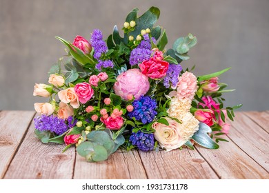 Close up view of a beautiful bouquet of mixed coloful flowers on wooden table. The concept of a flower shop and flower delivery as a family business, florist work. - Powered by Shutterstock