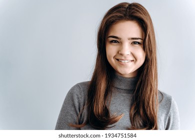 Close up view. Beautiful girl sincerely smiling on a gray background. Place for advertising, copy space.