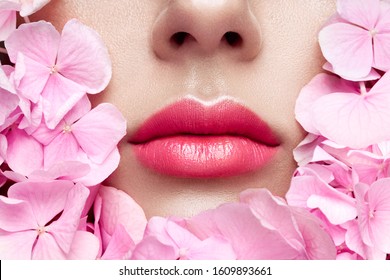 Close Up View Of Beautiful Woman Lips With Pink Lipstick In Flowers. Cosmetology, Drugstore Or Fashion Makeup Concept. Models Face In Decorated With Flowers