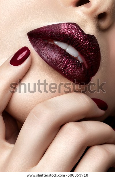 Close up view of beautiful woman\
lips with dark red mat lipstick and heart drawn in the center of\
lips. Woman touching her lips. Fashion make up. Studio\
shot