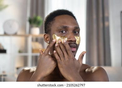 Close View Beauty Portrait Of Naked African Man With Golden Eye Patches Stands At Home On The Background Of A Modern And Stylish Apartment, Busy In Morning Routine, Caring For Beauty.