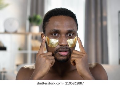 Close View Beauty Portrait Of Naked African Man With Golden Eye Patches Stands At Home On The Background Of A Modern And Stylish Apartment, Busy In Morning Routine, Caring For Beauty.