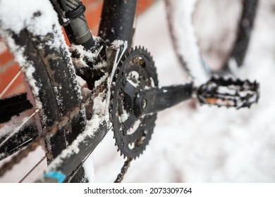 Close up view of a bike sprocket, chain and pedals covered with ice and snow at wintertime, bicycling at winter