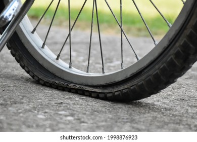 Close up view of bike which has flat tire and parked on the pavement, blurred background. Soft and selective focus on tire. - Powered by Shutterstock