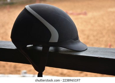 Close up view of  black Equestrian helmet with blurred horse farm view. Isolated Horse riding hat on the railing in the horse farm. - Powered by Shutterstock