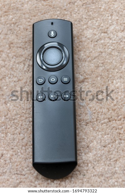 a close up view of a black smart tv remote placed on the\
carpet 