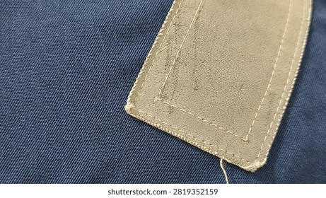 Close Up View of Blank Leather Patch Stitched on Dark Blue Fabric