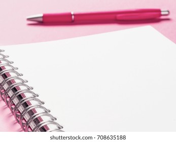 Close up view of blank note paper with pen on pink pastel background. Copy space. Back to school and education concept. Selective focus. Shallow DOF