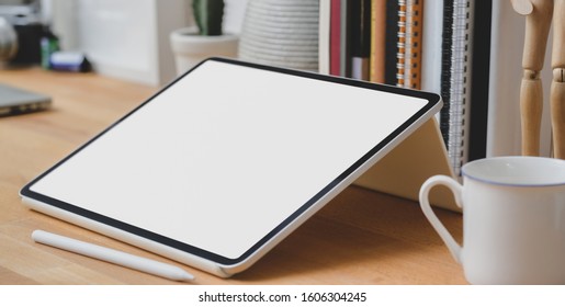 Close up view of blank screen tablet with office supplies and coffee cup in modern workspace 