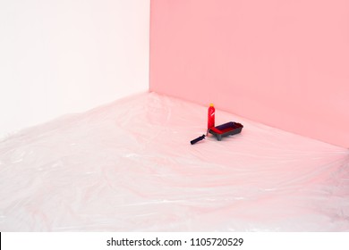 close up view of bottle, roller tray and paint roller in front of painted wall 