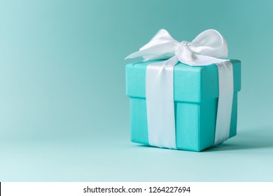 Close View Of The Box Tied With Silk Ribbon On Tiffany Blue Color Pastel Background. Gift Festive Selection. 