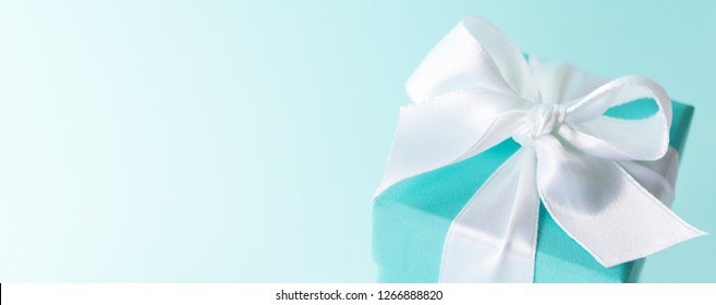 Close View Of The Box Tied With Silk Ribbon On Tiffany Blue Color Pastel Background. Gift Festive Selection. 