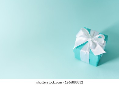 Close View Of The Box Tied With Silk Ribbon On Tiffany Blue Color Pastel Background. Gift Festive Selection. 