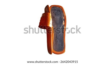 Close up view of the broken sole of an orange sandal, isolated on a white background.