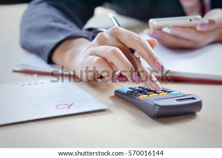 close view of a business woman hand calculating her monthly expenses during tax season.