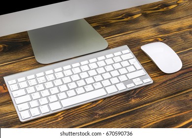 Close up view of a business workplace with  computer, wireless keyboard keys and mouse on old dark burned wooden table background. Office desk with copy space