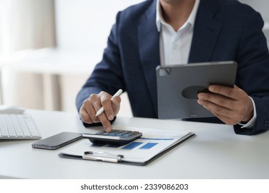 Close up view of businessman working in the office room while using calculator in the office room. - Powered by Shutterstock