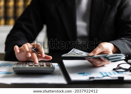 close up view of businesswomen or accountant counting dollar banknote with using calculator to calculate at the workplace, auditor, paperwork, bookkeeper, cash flow, investment, and financial concept.