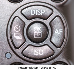 Close up view of a camera control panel showing buttons for display, autofocus, ISO settings, and the OK function, suitable for photographers adjusting settings during shoots.