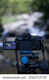 Close view of a camera LCD screen displaying a waterfall scene during shooting, emphasizing live view and creative composition.