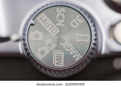 Close up view of a camera settings dial with icons indicating different shooting modes such as auto, scenic, and manual, highlighting the choice for photographers.