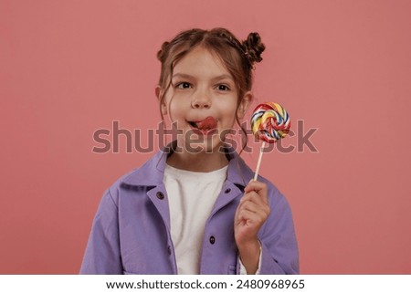 Close up view, with candy. Cute little girl is against pink background.