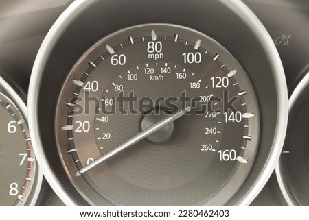 Close up view of car analog speedometer in miles and kilometers, partially visible tachometer
