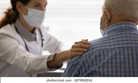 Close Up View Of Caring Female Doctor In Facial Mask Touch Support Elderly Patient. Supportive Woman GP Or Nurse In Protective Facemask Comfort Unhealthy Elderly Man At Consultation. Corona Concept.