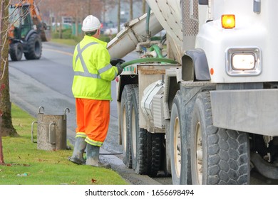 Close View Of A Cement Truck Driver Adjusting The Chute That Will Pour Liquid Cement On A Construction Site. 