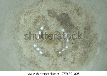 Close up view of ceramic pottery interior featuring detailed crazing lines and stained aged glaze patterns on cream surface.