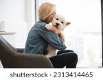 Close up view of cheerful caucasian lady in denim shirt snuggling into soft dog
