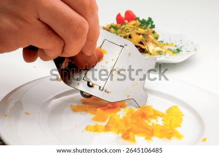Close up view of a chef grating bottarga, a luxurious delicacy crafted from cured fish roe, while skillfully preparing a gourmet dish in a bustling professional kitchen